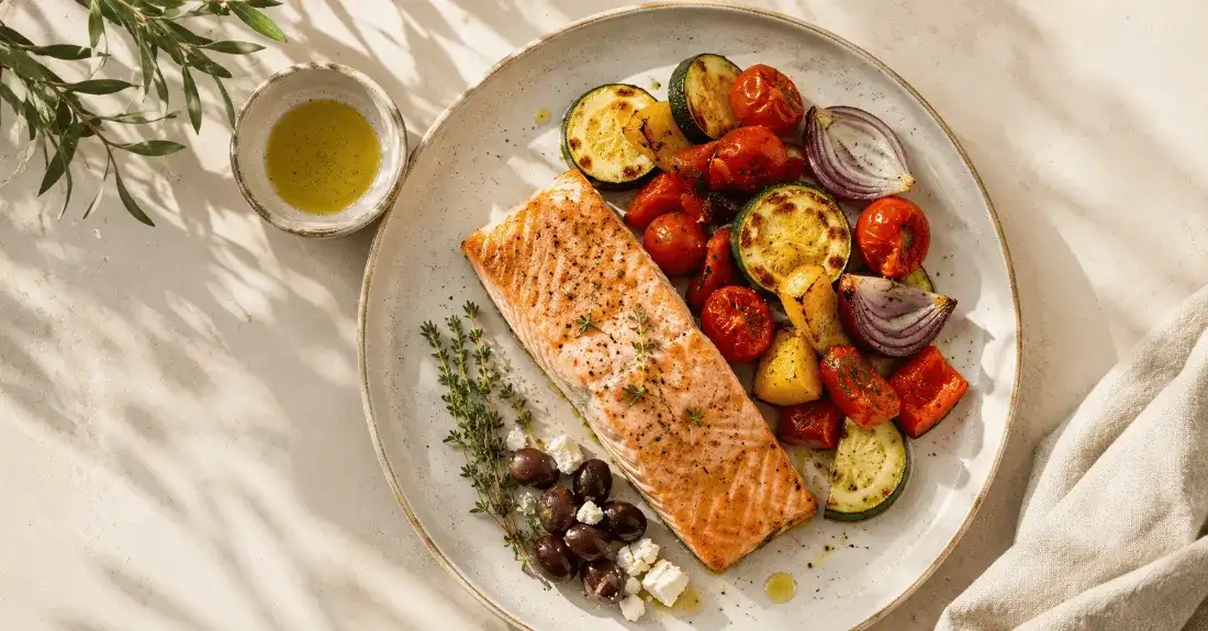 Home Overhead Mediterranean plate with baked salmon, roasted vegetables, olives, feta and olive oil