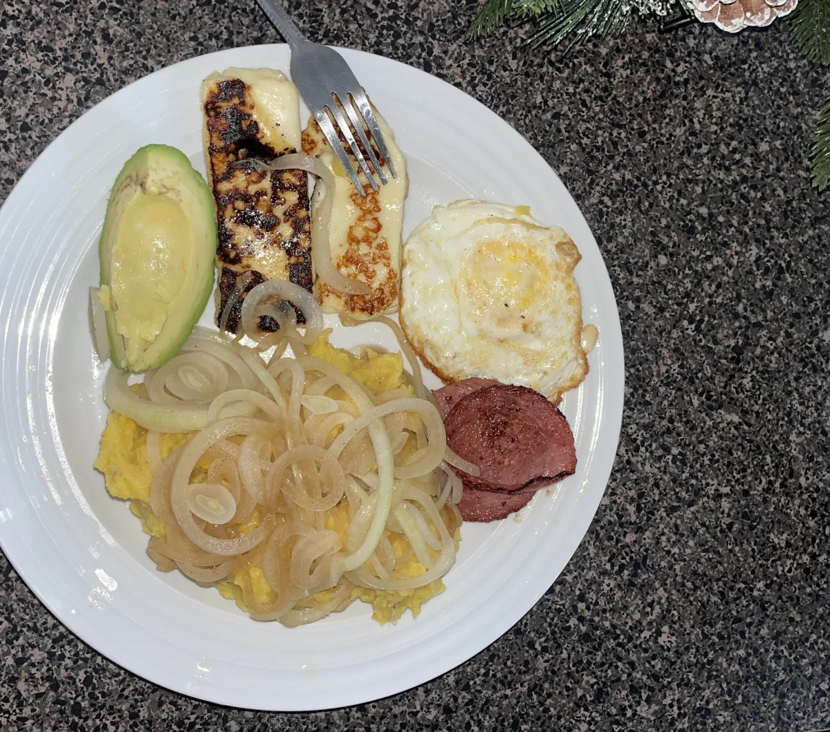 About Homemade Dominican plate of mangu with onions, fried cheese, salami, fried egg and avocado